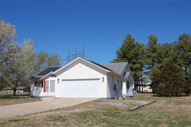 view of property exterior with roof mounted solar panels, a lawn, a garage, and concrete driveway