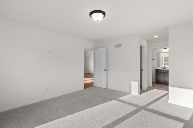 unfurnished bedroom featuring baseboards, connected bathroom, visible vents, and carpet