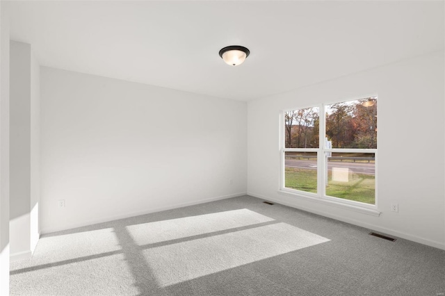 empty room featuring carpet floors, baseboards, and visible vents