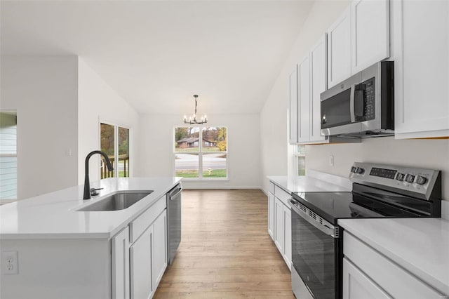 kitchen featuring light countertops, appliances with stainless steel finishes, lofted ceiling, a sink, and a notable chandelier