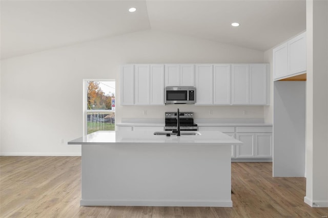 kitchen featuring light countertops, a sink, appliances with stainless steel finishes, a kitchen island with sink, and white cabinets
