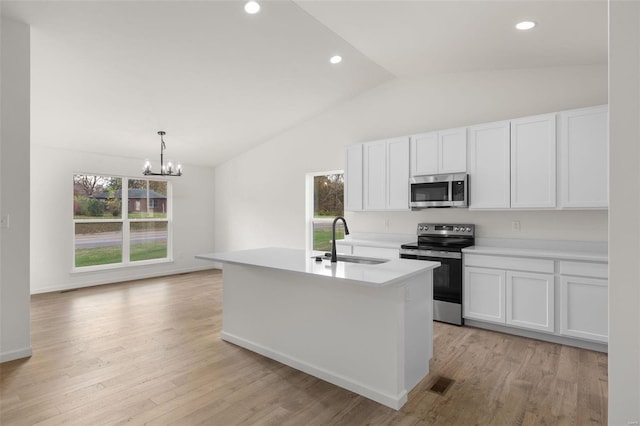 kitchen with a sink, light wood finished floors, appliances with stainless steel finishes, a center island with sink, and visible vents