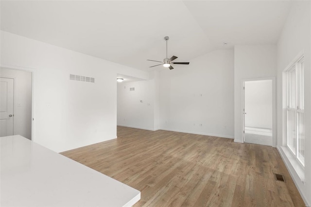 empty room with light wood finished floors, vaulted ceiling, ceiling fan, and visible vents