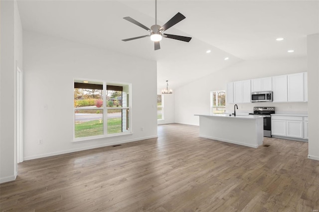 unfurnished living room with ceiling fan with notable chandelier, baseboards, light wood finished floors, and recessed lighting