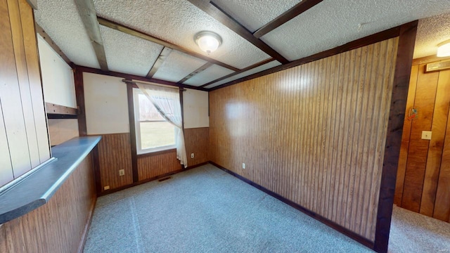bonus room with visible vents, wooden walls, light colored carpet, a textured ceiling, and a wainscoted wall