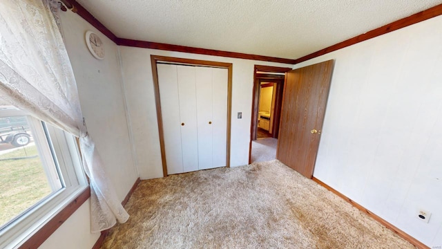 unfurnished bedroom featuring ornamental molding, carpet, a closet, and a textured ceiling