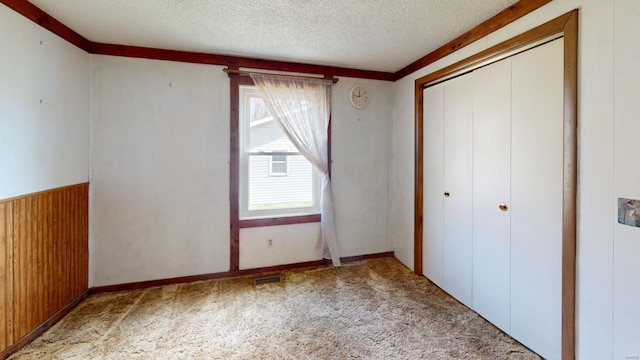 unfurnished bedroom with a closet, carpet flooring, a textured ceiling, and multiple windows