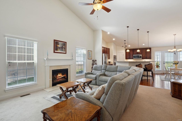 living area with light carpet, ceiling fan with notable chandelier, visible vents, and plenty of natural light