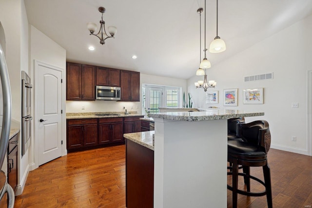 kitchen with dark wood-style floors, appliances with stainless steel finishes, a chandelier, and visible vents