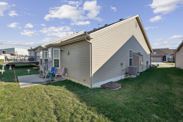 rear view of property featuring cooling unit, a deck, a patio area, and a yard