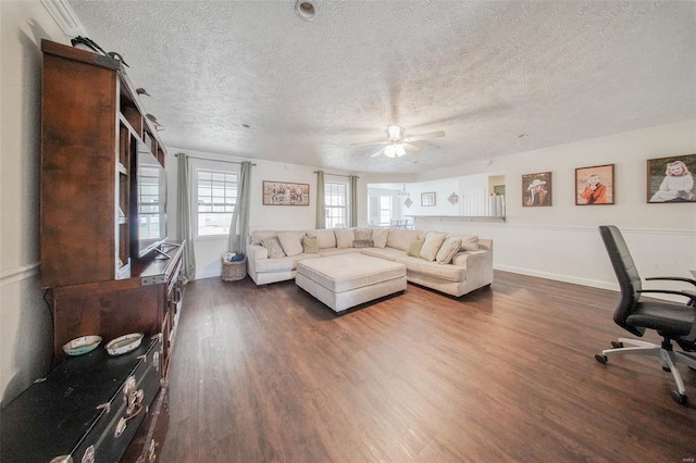 living area featuring dark wood finished floors, baseboards, a textured ceiling, and a ceiling fan