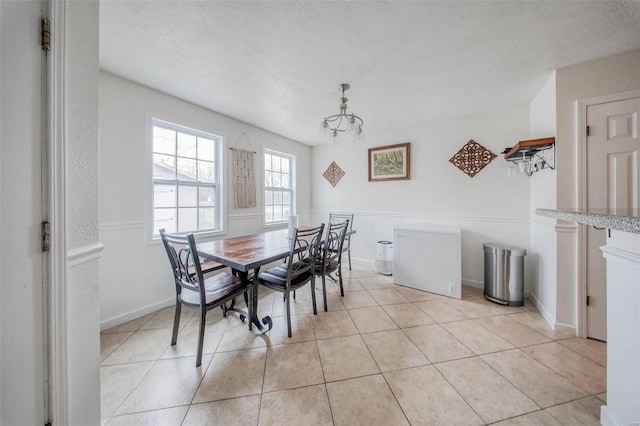 dining space with light tile patterned flooring, baseboards, a notable chandelier, and a textured ceiling