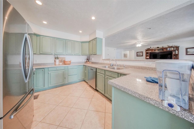 kitchen featuring a sink, green cabinets, appliances with stainless steel finishes, a textured ceiling, and light tile patterned floors