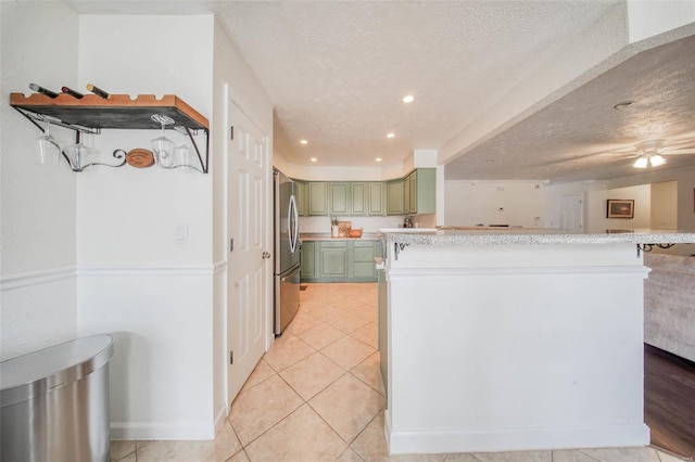 kitchen featuring green cabinets, light countertops, freestanding refrigerator, and a textured ceiling