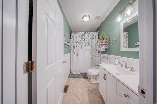full bath featuring toilet, vanity, a textured ceiling, tile patterned flooring, and visible vents