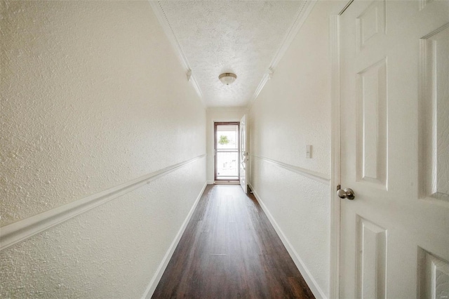 hallway with dark wood-style flooring, crown molding, a textured wall, and a textured ceiling