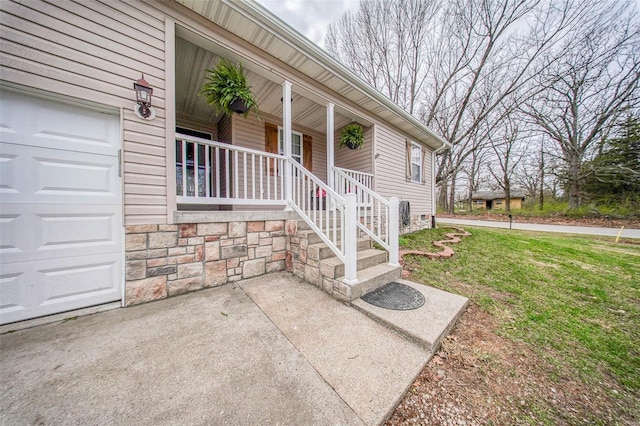 doorway to property with a porch, a garage, and a yard