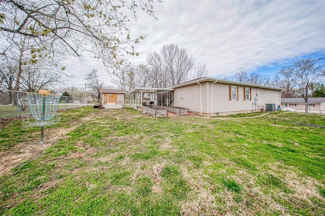 view of yard with an outdoor structure, a garden, central AC, and fence