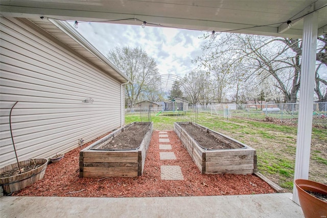 view of yard with a garden, a fenced backyard, and a trampoline