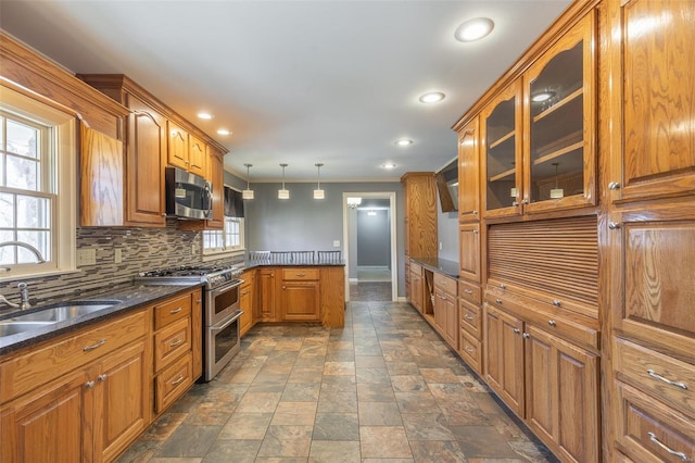 kitchen with stainless steel appliances, backsplash, a sink, brown cabinetry, and glass insert cabinets