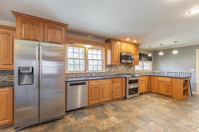 kitchen featuring a peninsula, dark countertops, tasteful backsplash, appliances with stainless steel finishes, and a sink