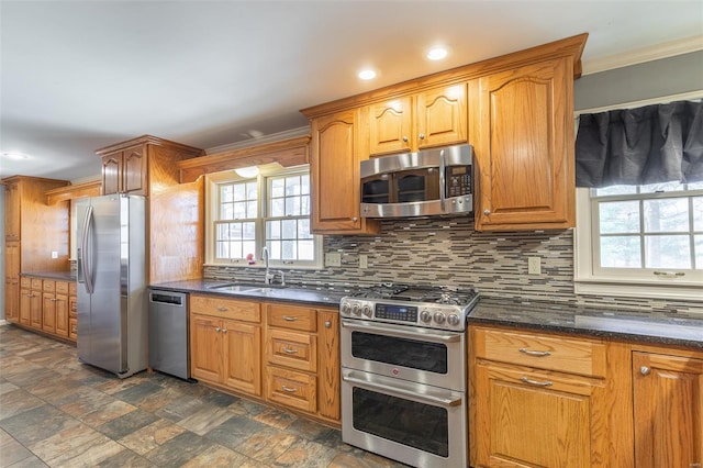 kitchen featuring tasteful backsplash, appliances with stainless steel finishes, stone finish flooring, and a wealth of natural light