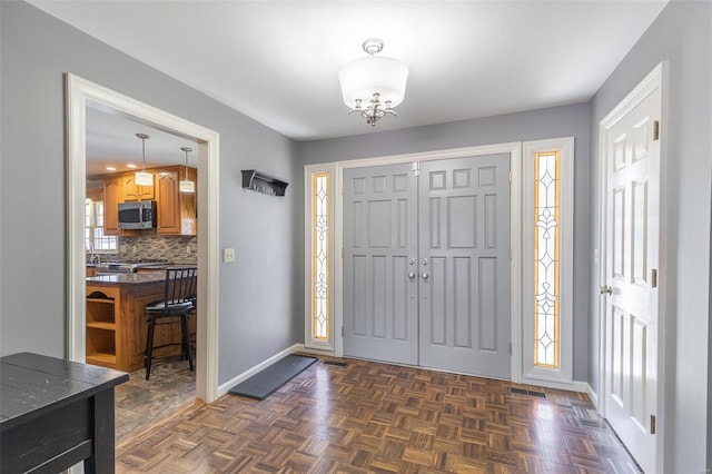 entrance foyer with baseboards, visible vents, and a chandelier