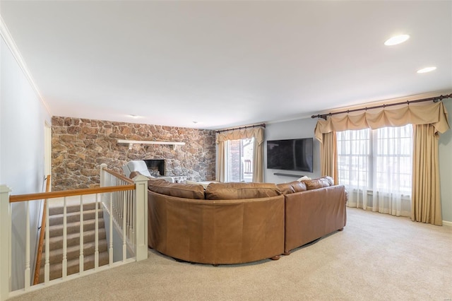 unfurnished living room with a stone fireplace, crown molding, and carpet