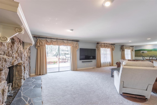 carpeted living area with a stone fireplace and baseboards
