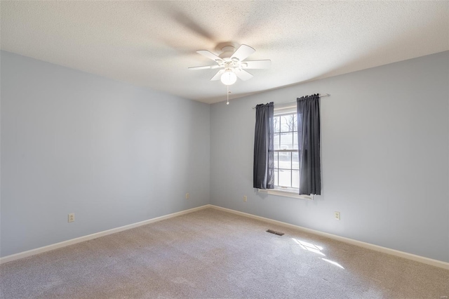 carpeted empty room featuring baseboards, a textured ceiling, visible vents, and a ceiling fan