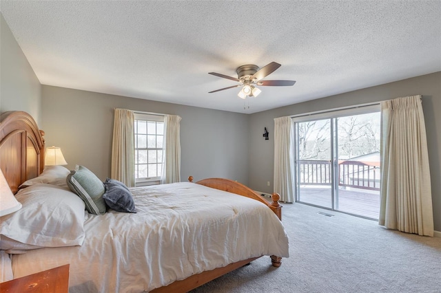 carpeted bedroom featuring a ceiling fan, a textured ceiling, access to exterior, and visible vents