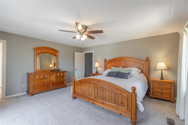 bedroom with baseboards, visible vents, a ceiling fan, and light carpet