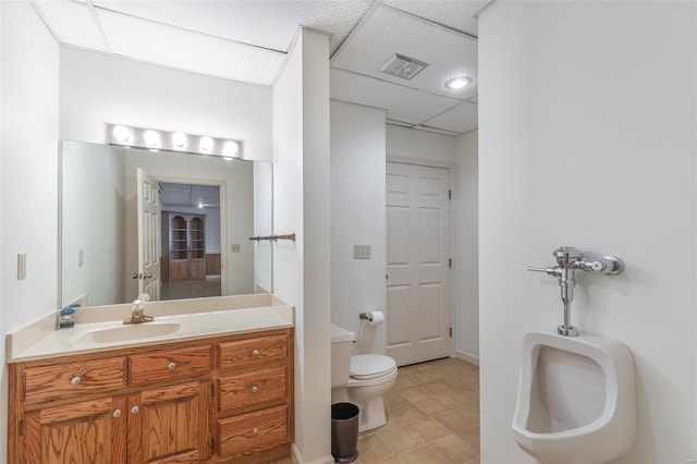 bathroom featuring a drop ceiling, toilet, vanity, and visible vents