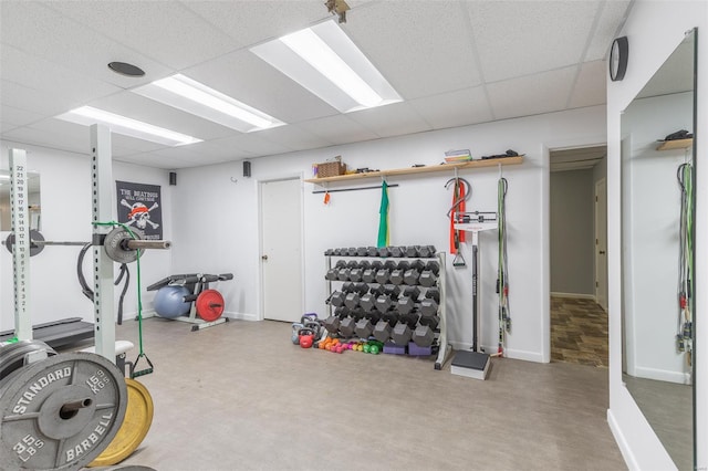 workout area featuring baseboards and a drop ceiling