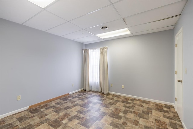 empty room featuring baseboards, visible vents, and a drop ceiling