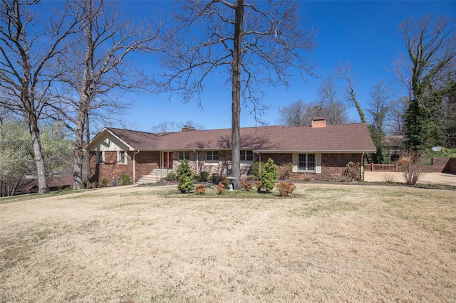 ranch-style house featuring brick siding, a front yard, and a chimney