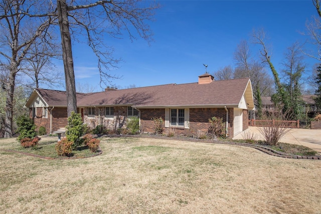 ranch-style home with a chimney, a front yard, brick siding, and concrete driveway