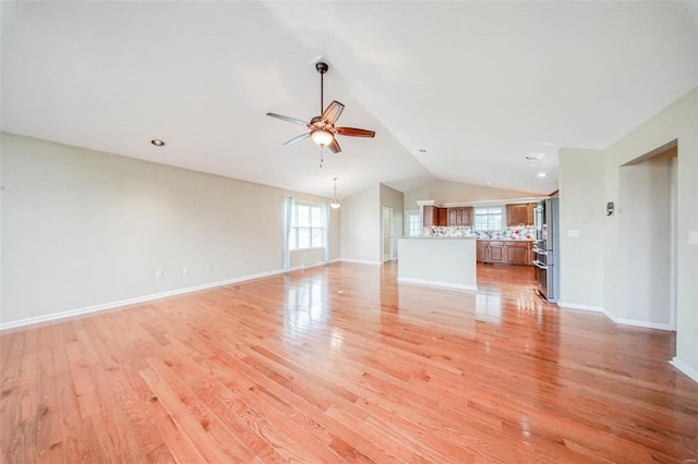 unfurnished living room with plenty of natural light, ceiling fan, light wood-style flooring, and lofted ceiling