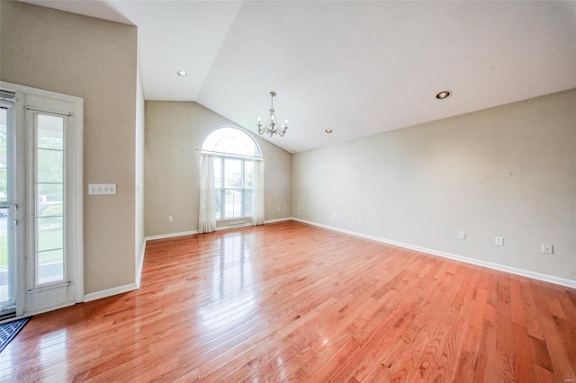 interior space featuring baseboards, a notable chandelier, vaulted ceiling, and light wood-type flooring