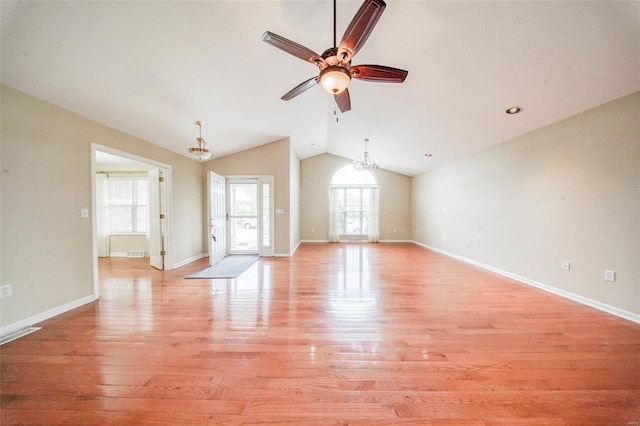 unfurnished living room with plenty of natural light, light wood finished floors, ceiling fan with notable chandelier, and lofted ceiling