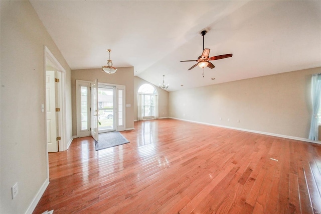 unfurnished living room with light wood-style floors, baseboards, ceiling fan with notable chandelier, and lofted ceiling