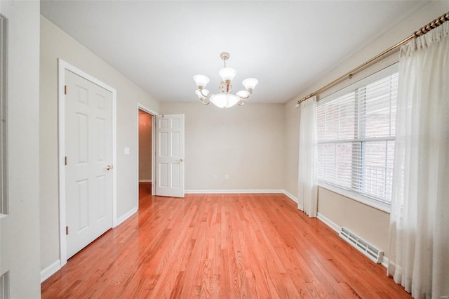 unfurnished dining area with a notable chandelier, light wood-type flooring, and visible vents