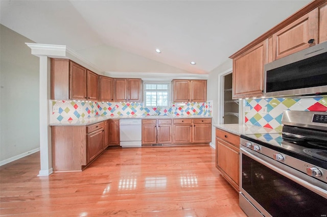 kitchen featuring decorative backsplash, a sink, light wood-style flooring, appliances with stainless steel finishes, and vaulted ceiling