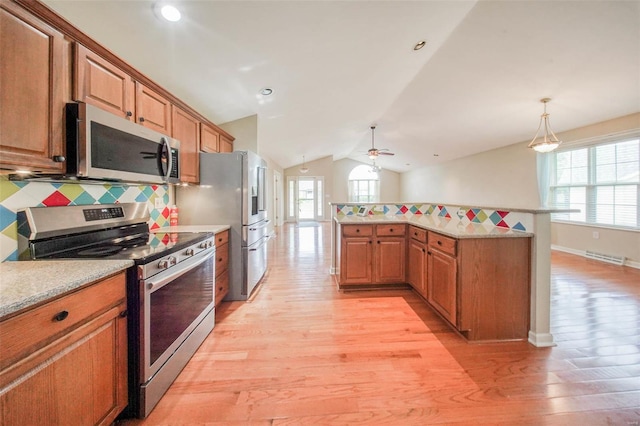 kitchen featuring appliances with stainless steel finishes, a wealth of natural light, light wood-style flooring, and lofted ceiling