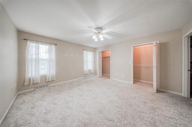 unfurnished bedroom with a ceiling fan, visible vents, baseboards, two closets, and carpet flooring