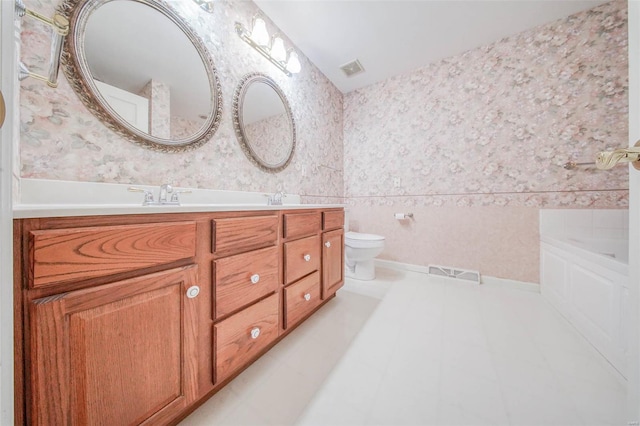 bathroom with double vanity, a sink, tile patterned floors, toilet, and wallpapered walls
