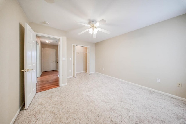 unfurnished bedroom with baseboards, a ceiling fan, a closet, and light colored carpet
