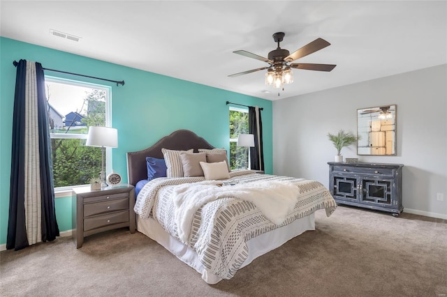 carpeted bedroom with baseboards, multiple windows, a ceiling fan, and visible vents