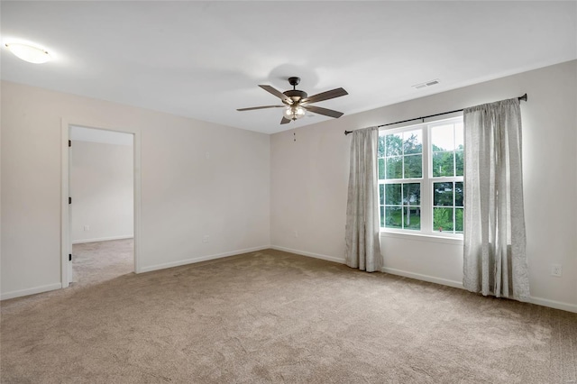 carpeted spare room with baseboards, ceiling fan, and visible vents