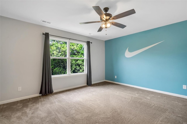 carpeted empty room with visible vents, a ceiling fan, and baseboards